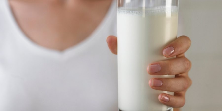 A womand holding a glass of milk wearing a white shirt