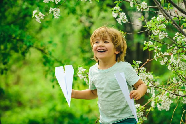 Child playing with a paper plane in an eco-friendly environment