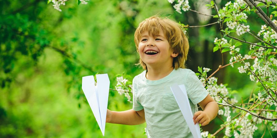 Child playing with a paper plane in an eco-friendly environment